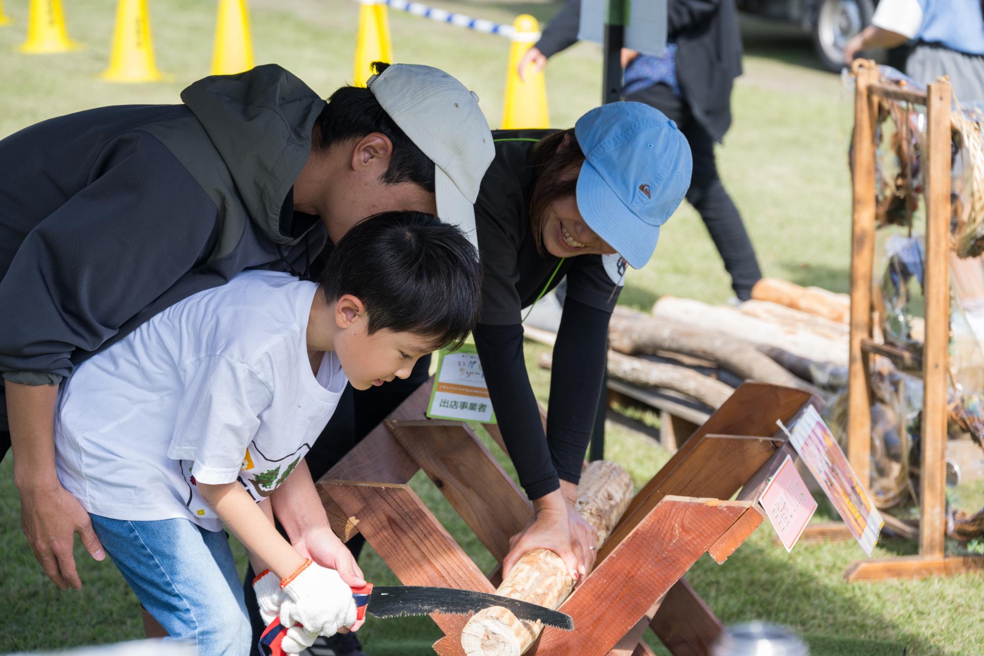 丸太切りをしている子供の画像