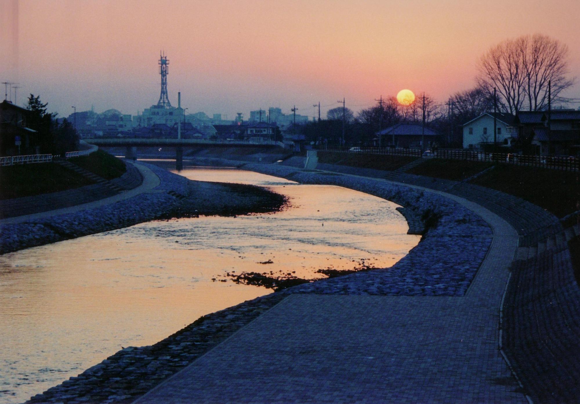 陽が沈む薄暗くなった川沿いを写した風景写真