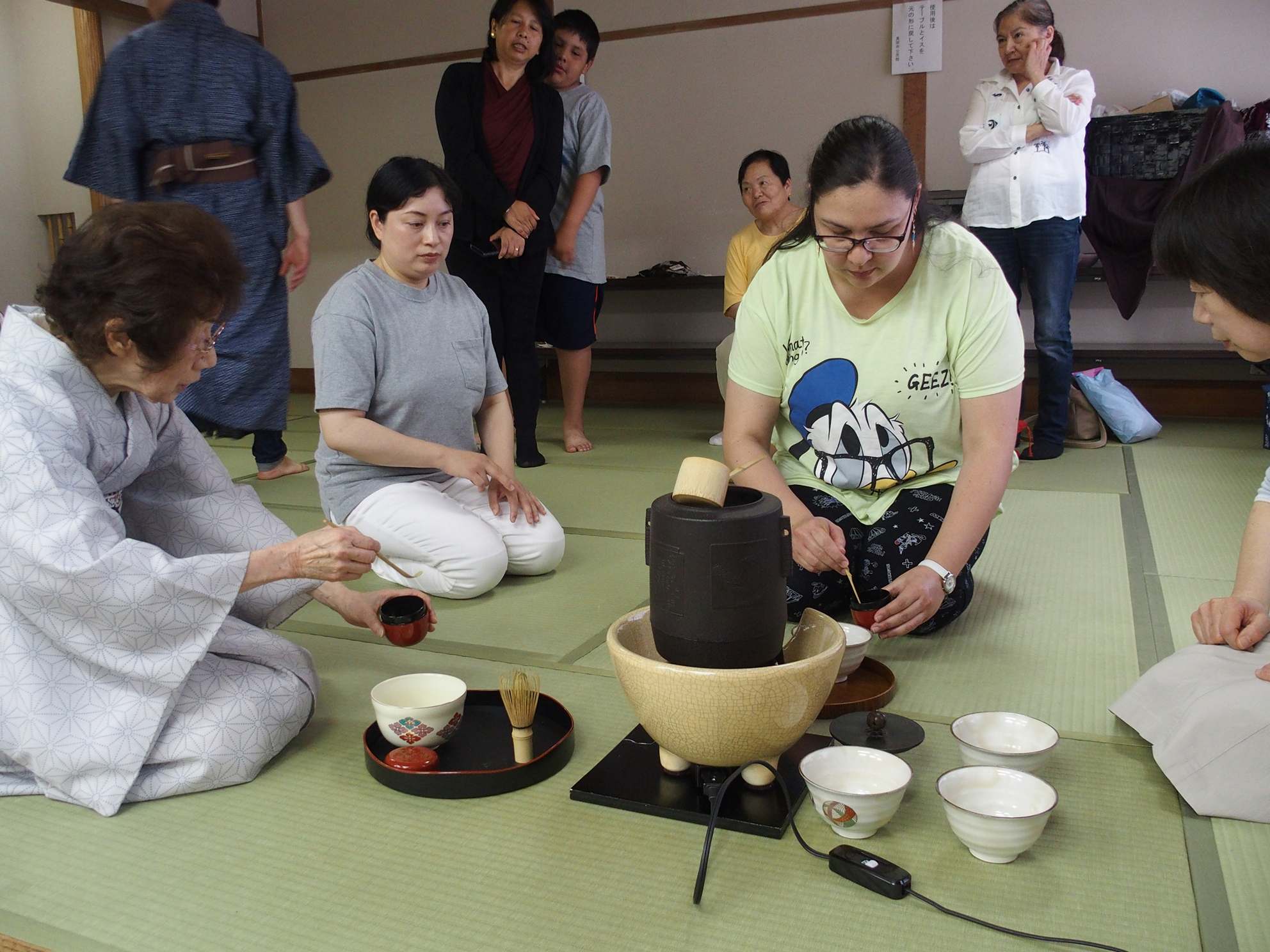 外国人女性が杉山先生の指導を受けながら茶道を体験している写真