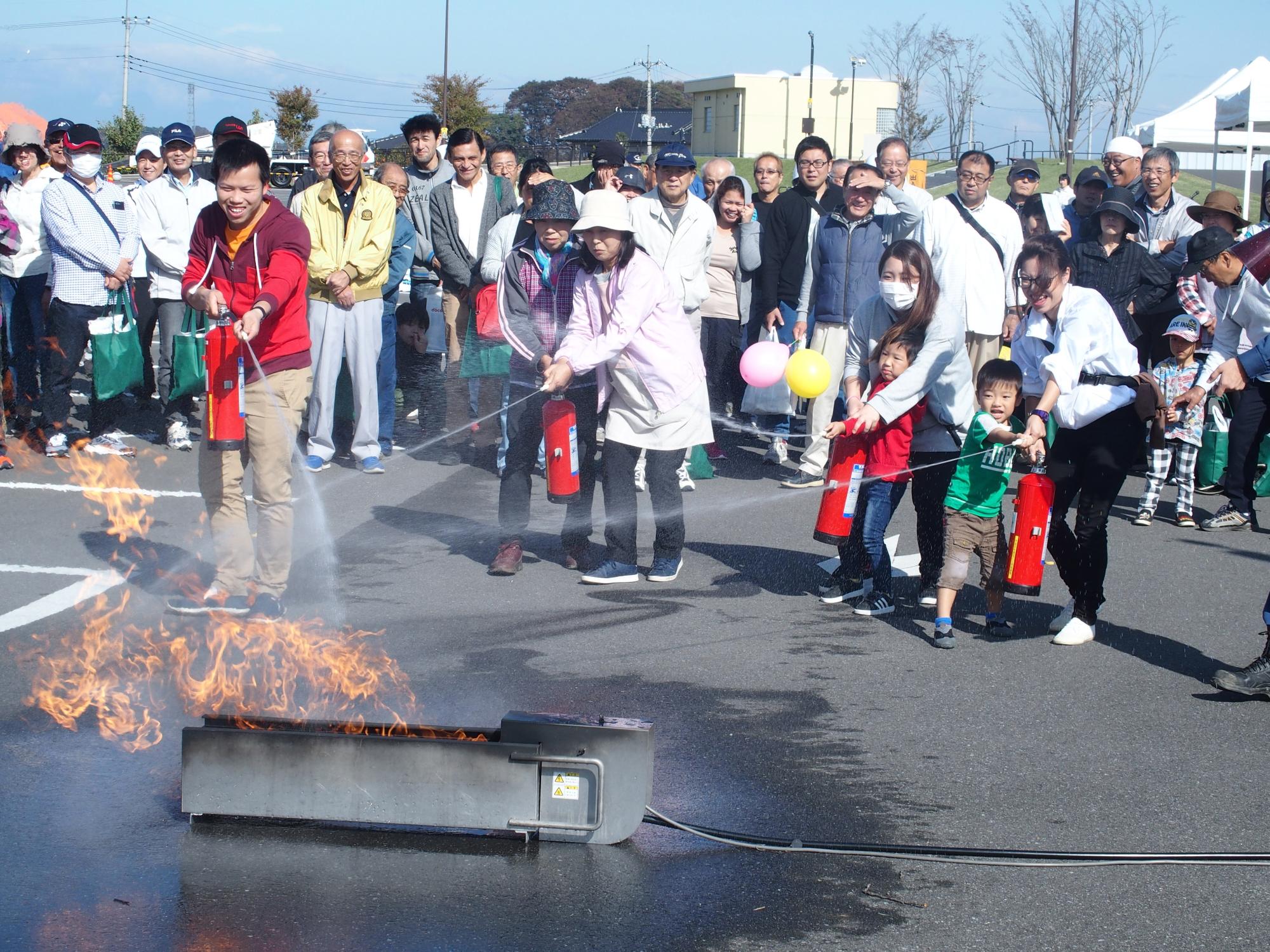 参加者の親子が消火器で火を消している写真