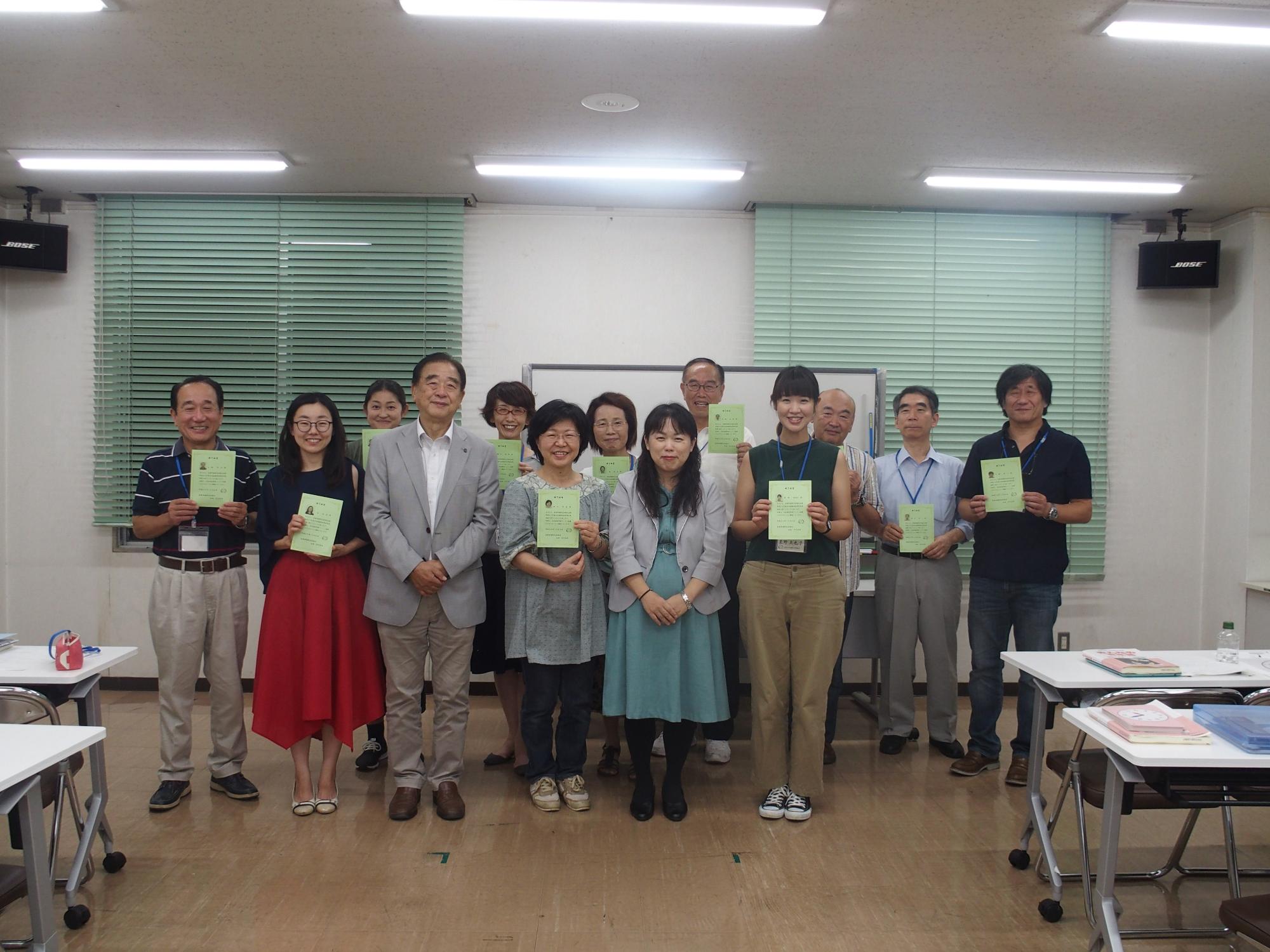 緑色の終了証書を手に記念撮影をしている日本語指導者養成講座参加者達の写真