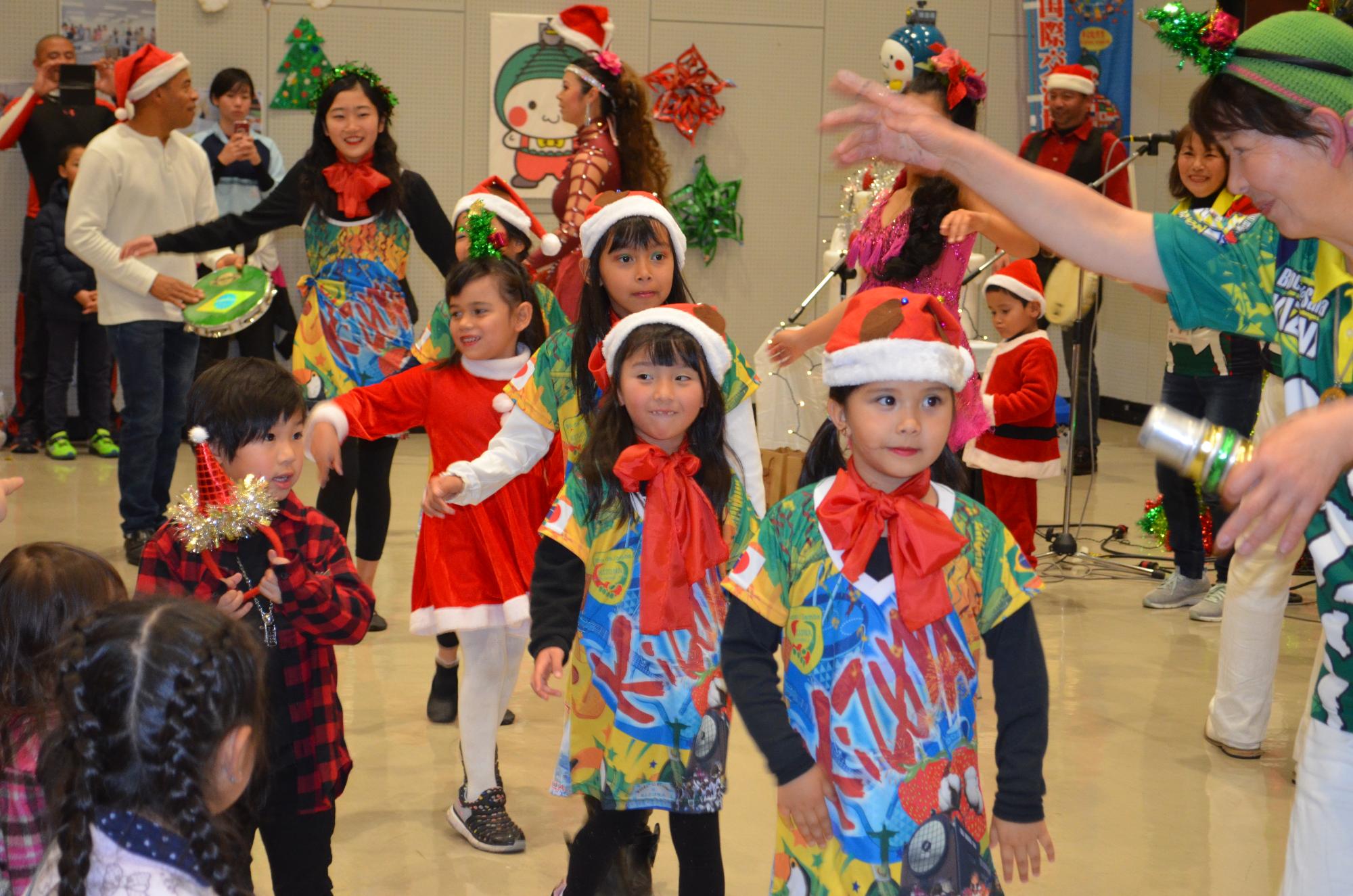 サンタクロースの衣装を着た子供たちが1列になって歩いている写真