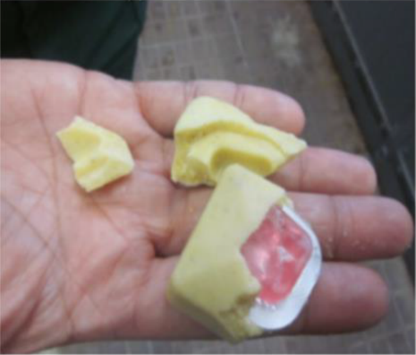 クリーム色で、ビスケット状のエサの中にピンク色のワクチンが入っている経口ワクチンを一部割って見せている写真