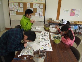 大人と子どもが、木型を削って、アクリル絵の具で色を塗っている。