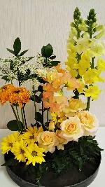 黄色やオレンジ色、クリーム色などの綺麗な花が生けられたフラワーデザインの写真
