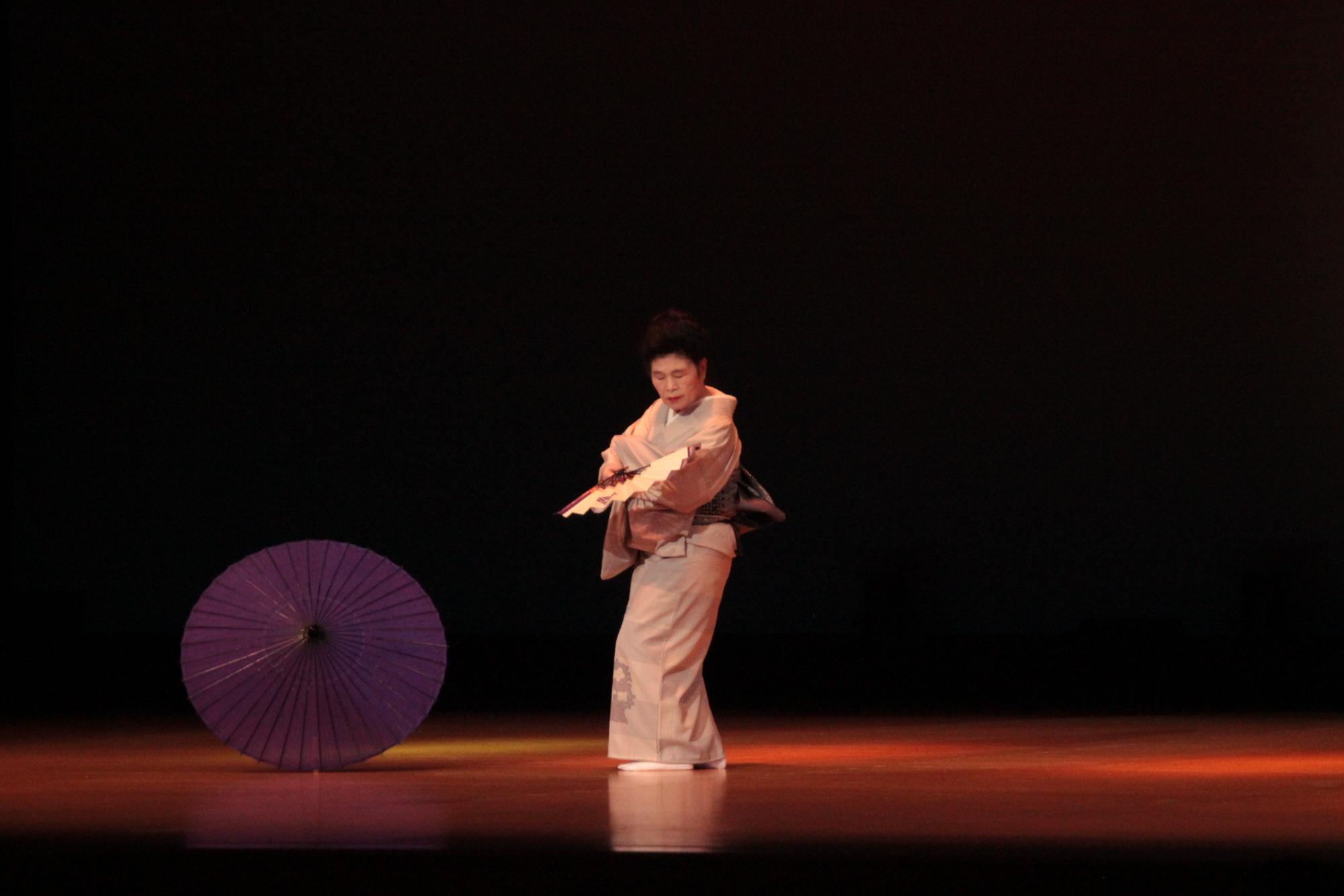 着物を着た女性が扇子を持って舞踊を披露している写真