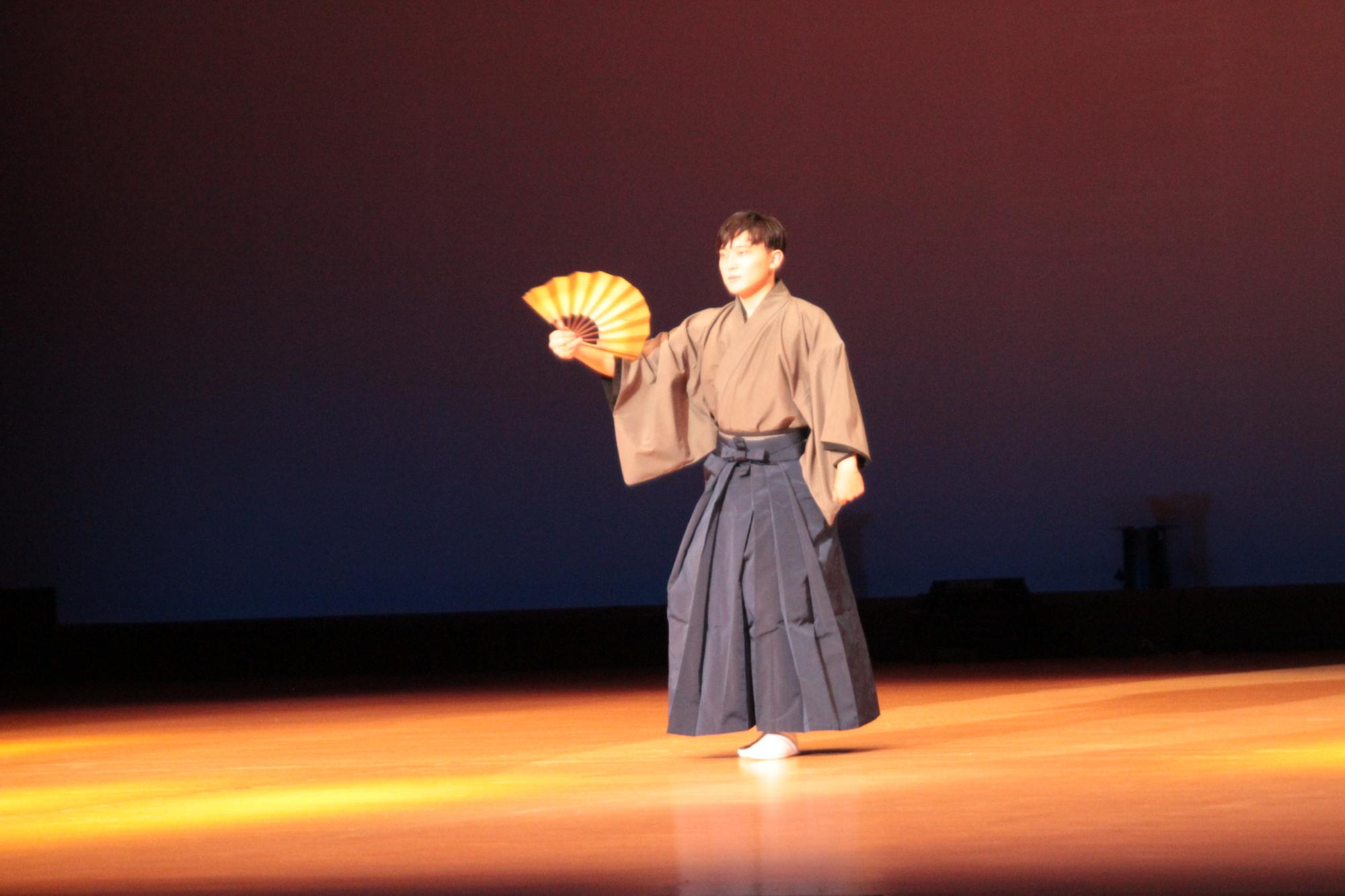 袴を着た男性が扇子を持って舞踊を披露している写真