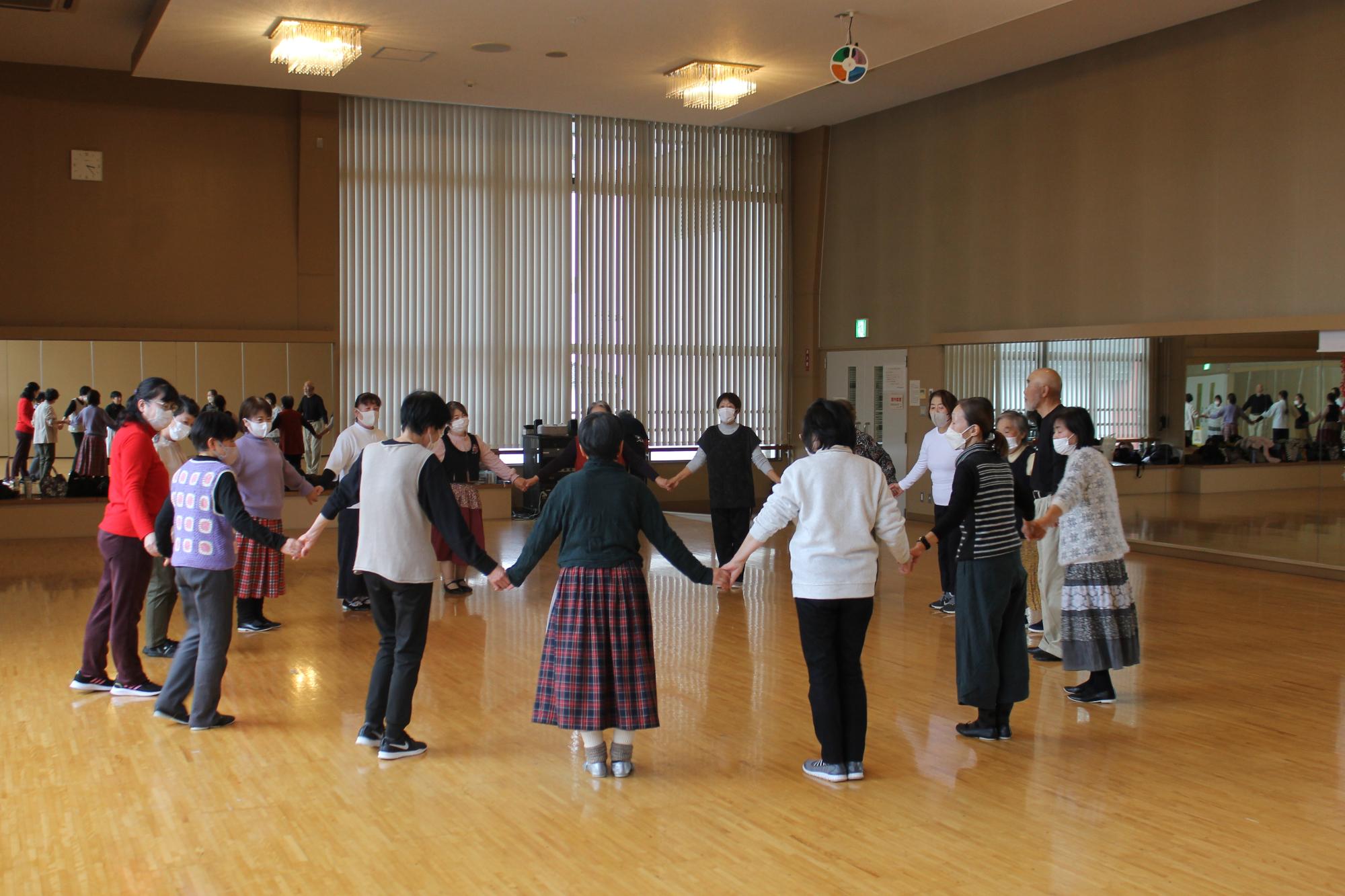 円になって手をつなぐ講師と受講生