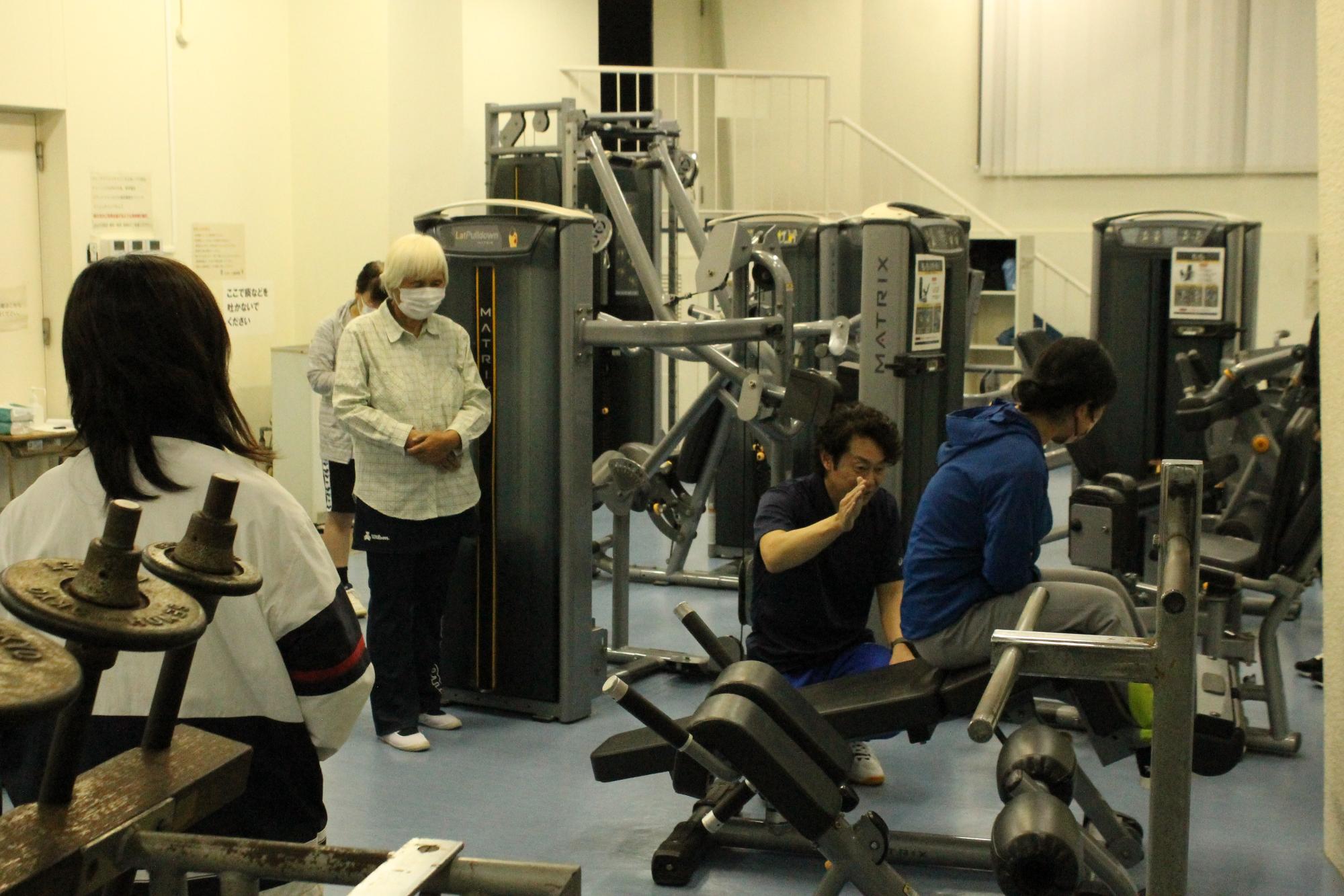 トレーニングマシンの効果的な使い方を教える講師と受講生