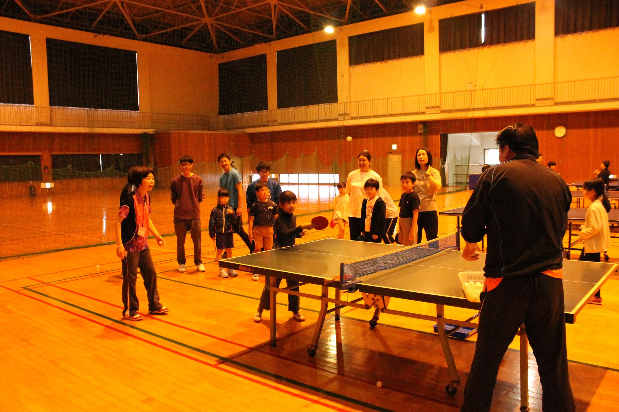 卓球のボールを打ち返すこどもとそれを見守る講師