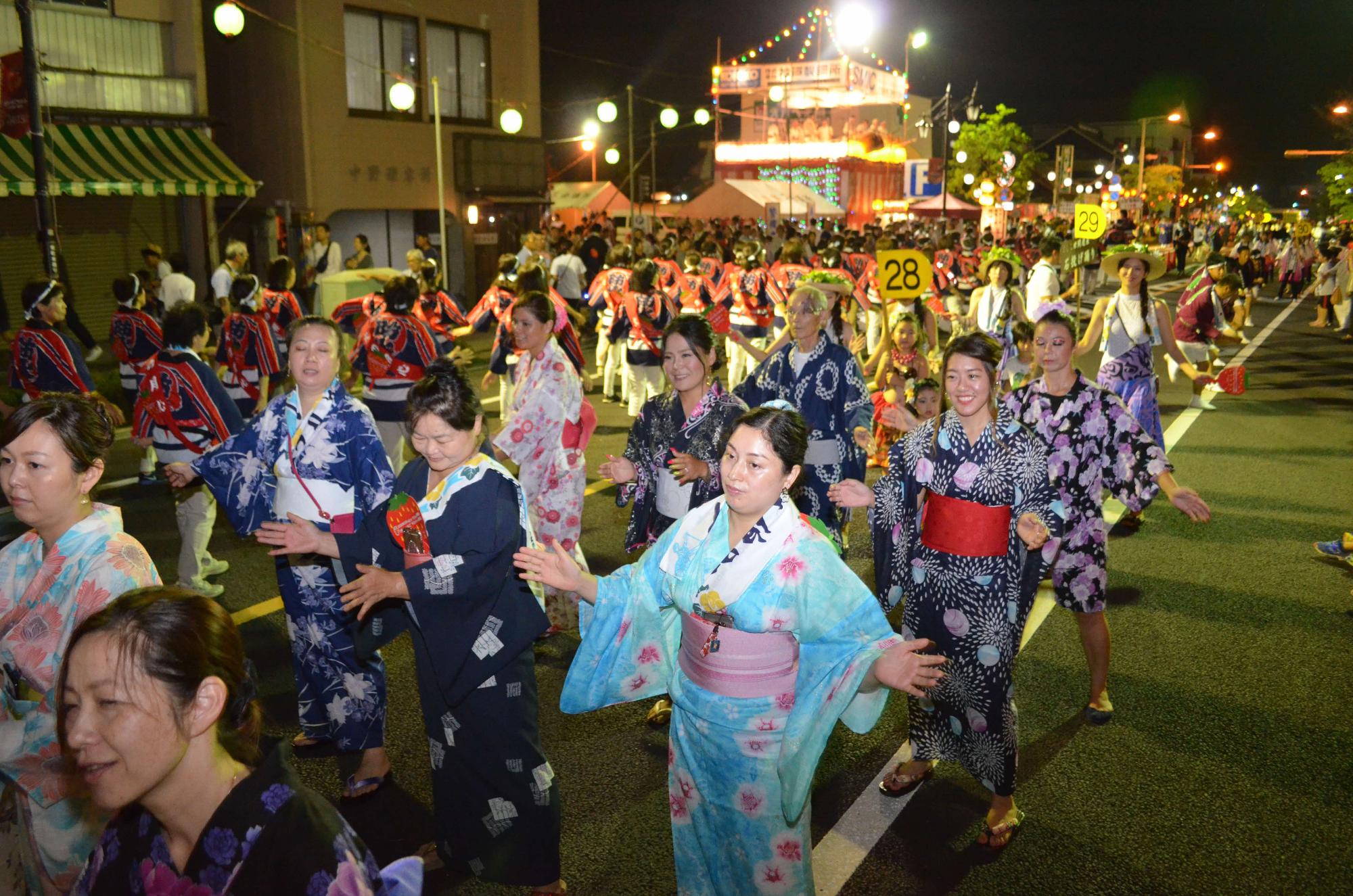 道路に広がって浴衣を着た人たちがもおか木綿踊りを踊っている写真