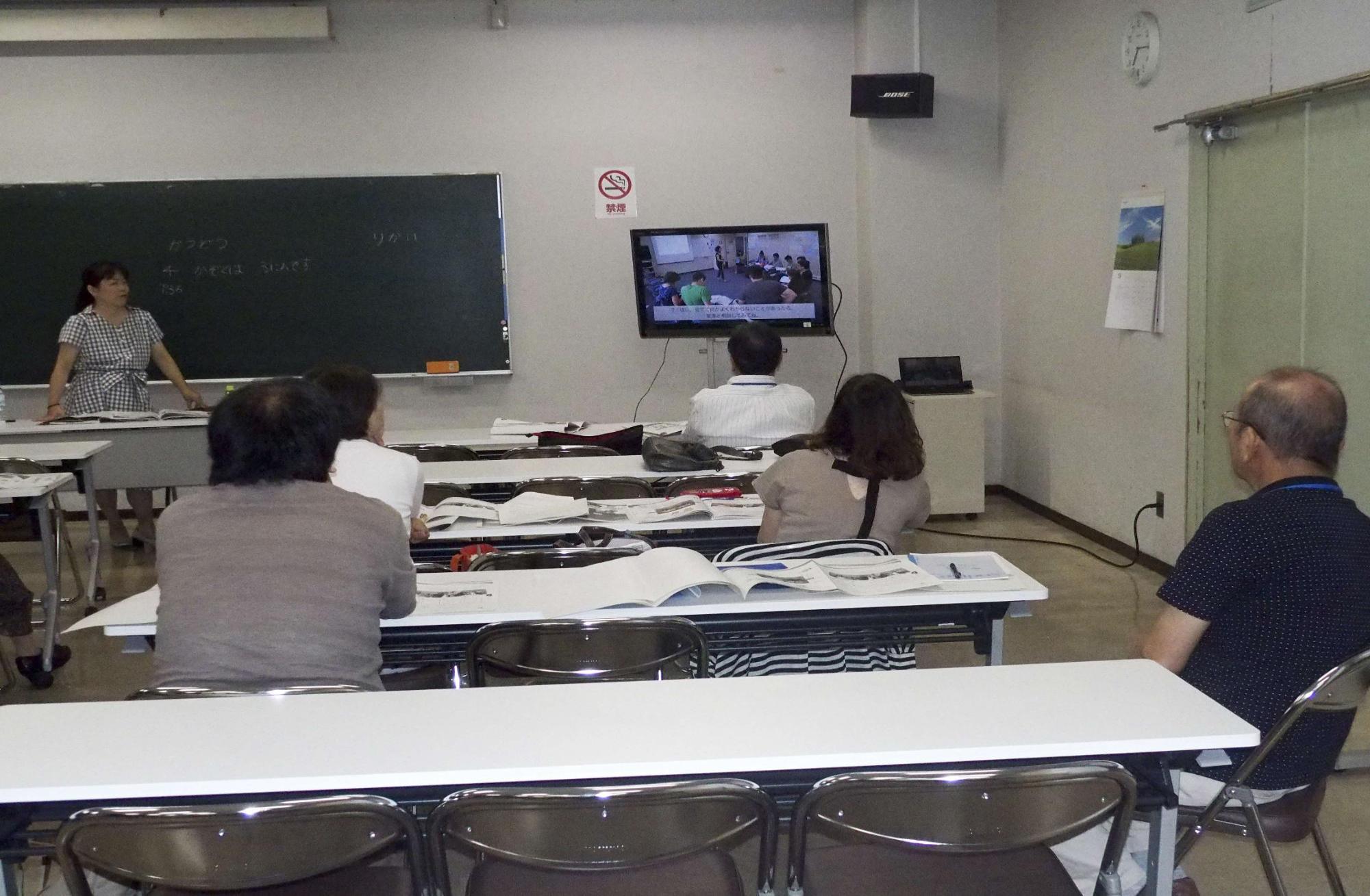 教室前方に置かれたテレビを見ながら講座が行われている様子を教室の後方から写した写真