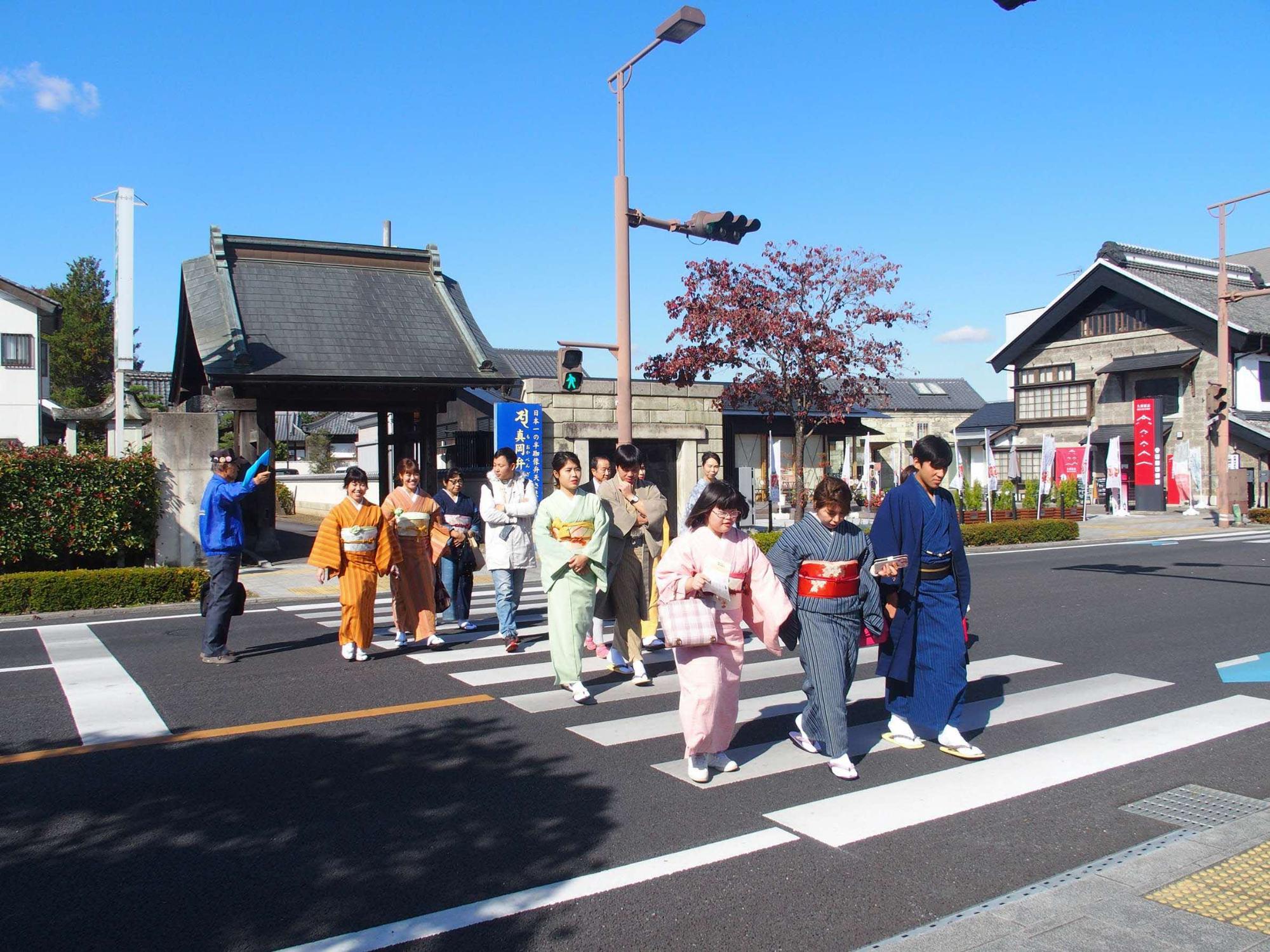 様々な色の着物を着た参加者達が横断歩道を渡っている写真