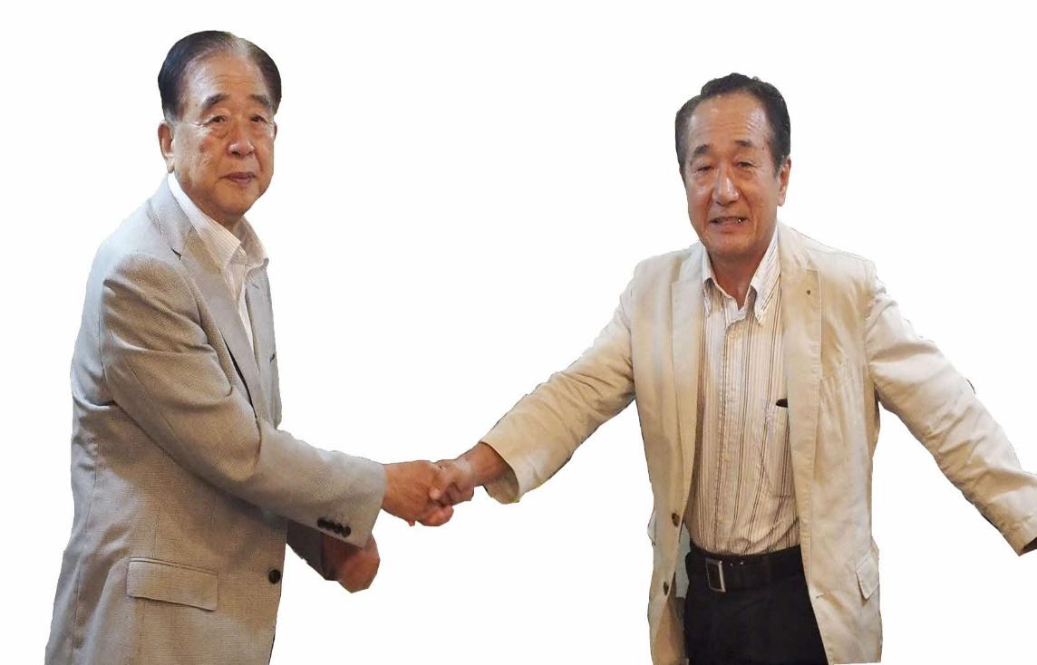 前会長の行川至孝さんと新会長の小堀辰夫さんが握手をしている写真