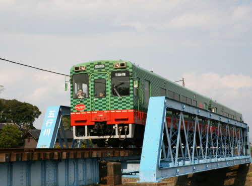 緑色と黒色の市松模様の気動車が鉄橋の上を走っている写真
