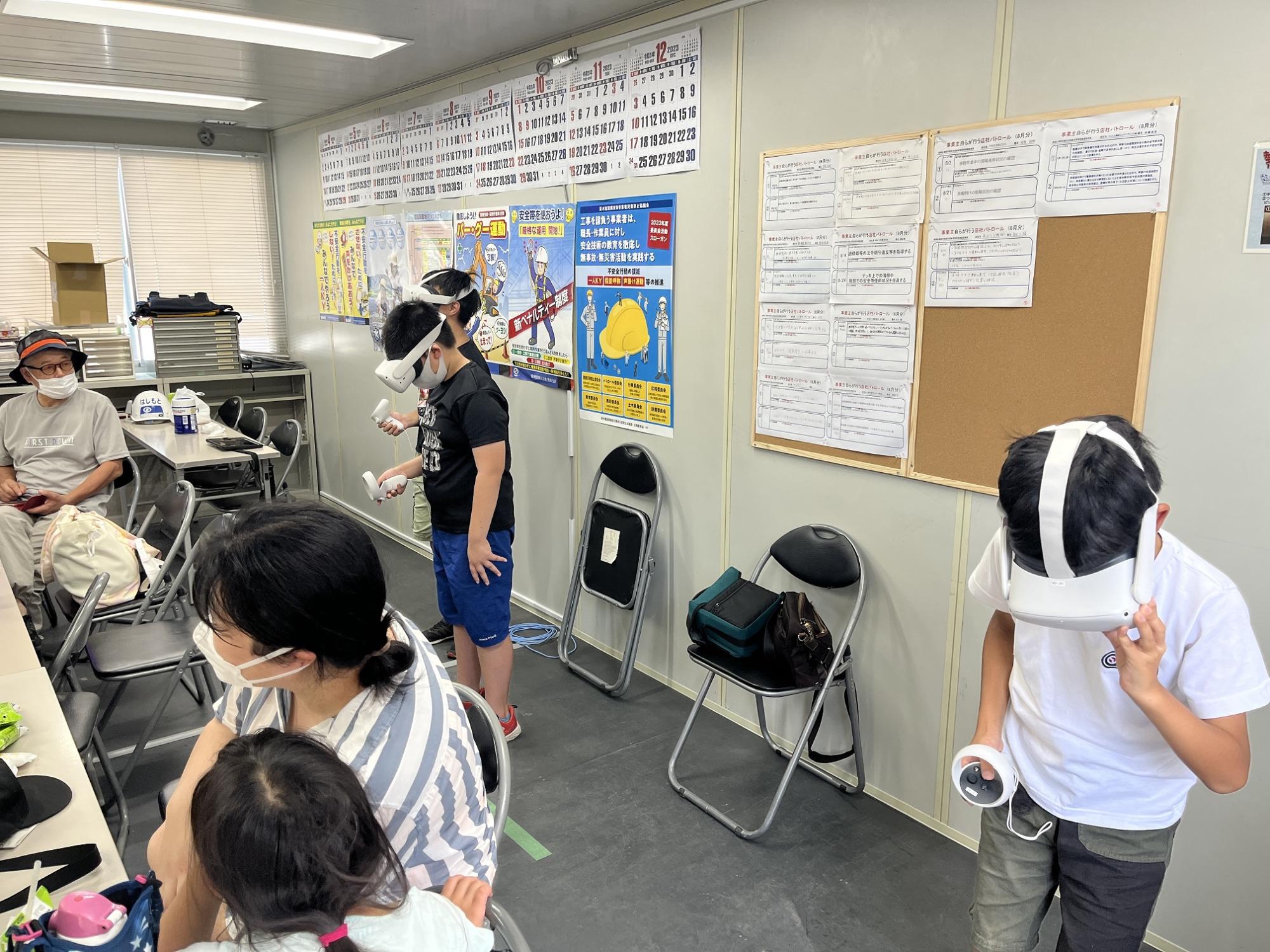 現場事務所でVRゴーグルをつけて施設内を疑似体験する小学生たち