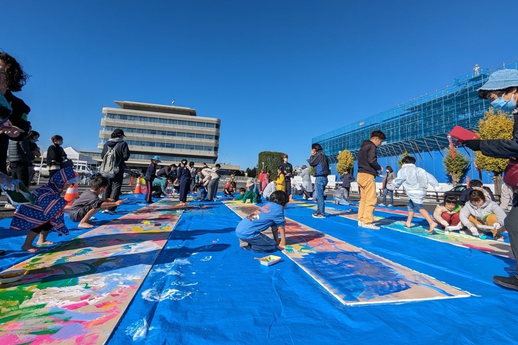 複合交流拠点仮囲いアートプロジェクト青空の下みんなでベニヤ板に絵を描く