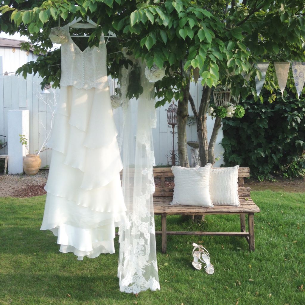 屋外の木にかけられている白いドレスとベールの写真