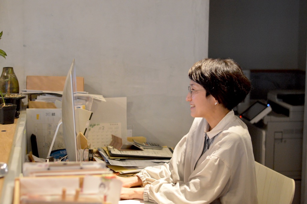 パソコンの前に座り作業をしている岡 綾さんを横から写した写真