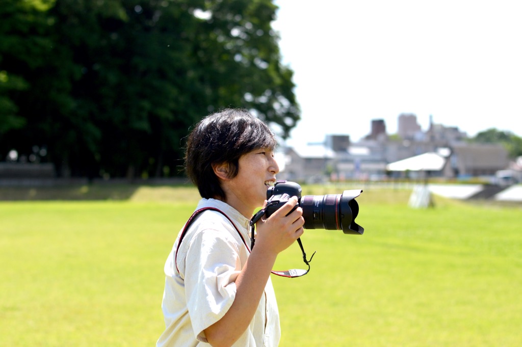 カメラを顔の近くで持ち、遠くを見ている柴 美幸さんの写真