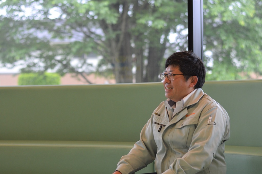 緑色のソファーに腰かけ笑顔を見せている上澤 宏行さんの写真